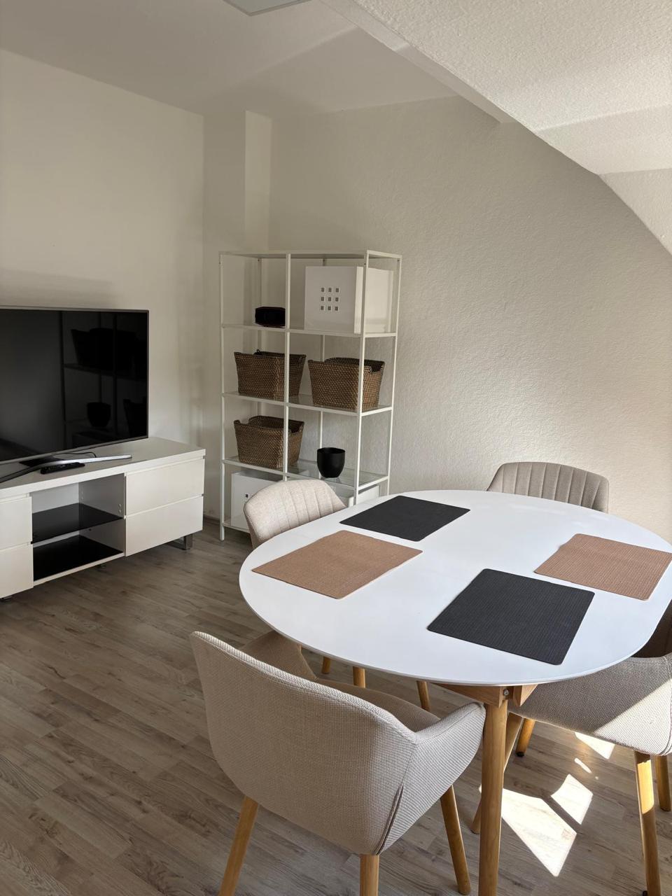 Wohnbereich mit Fernseher, Regal und Esstisch